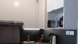 Una cocina moderna con armarios blancos, una campana extractora de acero inoxidable, un horno empotrado y un lavavajillas.