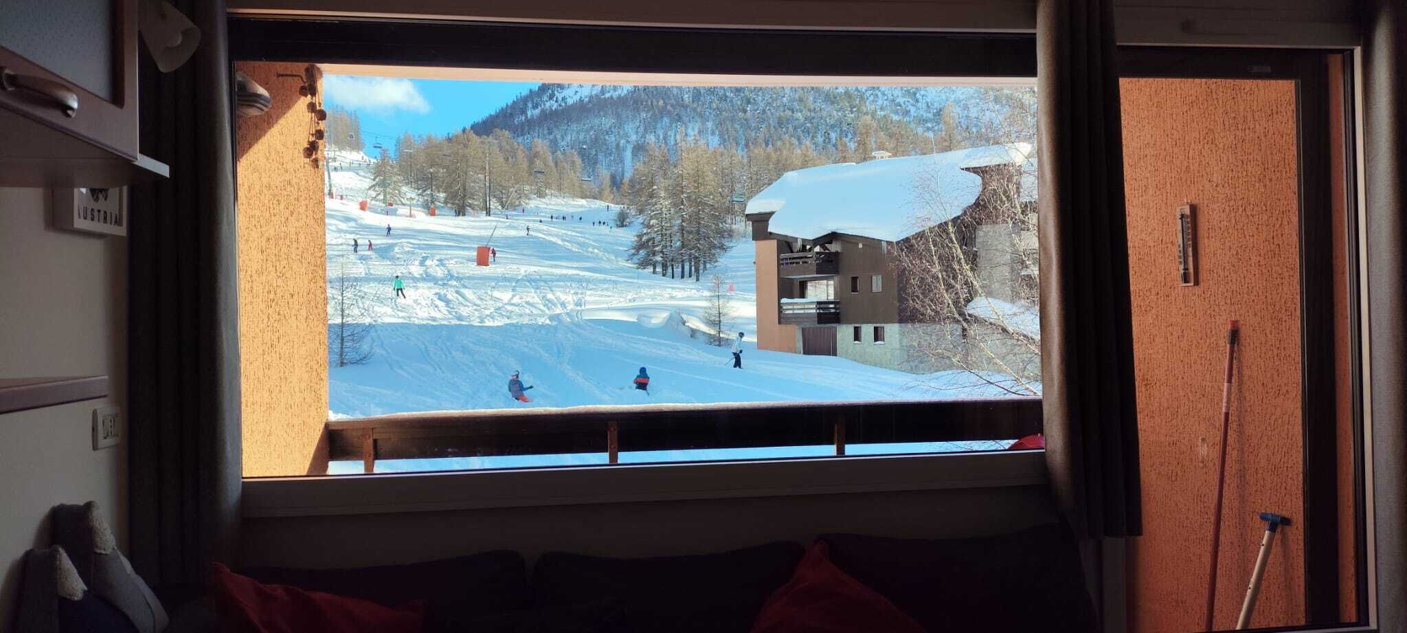 A window view of a ski resort with a building and a snow-covered slope.