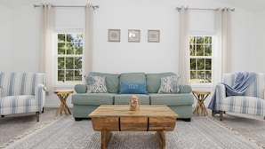 A living room with a green sofa, two striped armchairs, a wooden coffee table, and a patterned rug. - Coastal Retreat, Close to the Beach (Pawleys Island)