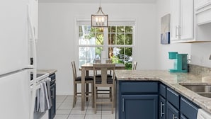A kitchen with a dining table, chairs, a coffee maker, and cabinets. - Coastal Retreat, Close to the Beach (Pawleys Island)