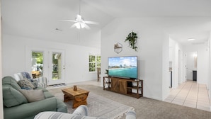 A spacious living room with a green sofa, a wooden coffee table, and a large flat-screen TV. - Coastal Retreat, Close to the Beach (Pawleys Island)