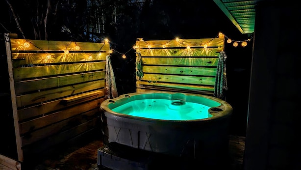 A hot tub surrounded by wooden fences with string lights. - Coastal Retreat, Close to the Beach (Pawleys Island)