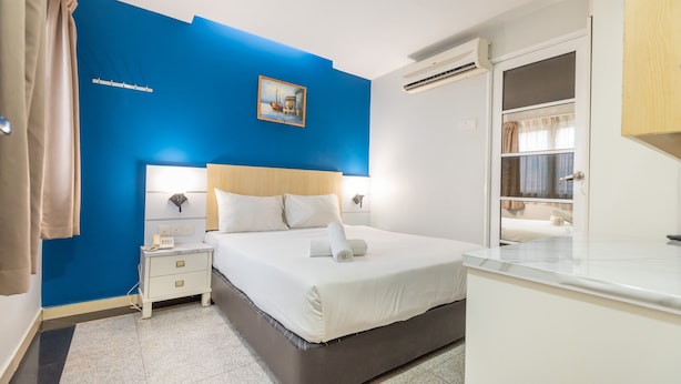 A bedroom with a large bed, bedside tables, a nightstand, a painting on the wall, and an air conditioning unit. - Best View SS15 (Subang Jaya)