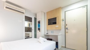 A hotel room with a bed, a TV mounted on the wall, a small desk with a mirror, and a door. - Best View SS15 (Subang Jaya)