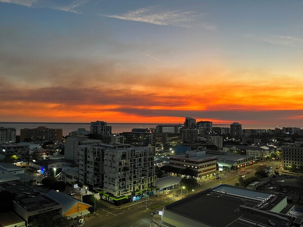 A cityscape at sunset with buildings and a road. - Darwin City Sea View Apartment with Balcony  (Darwin City)