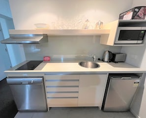Prepare meals with ease in this kitchen featuring a stainless steel sink, microwave, and compact dishwasher.