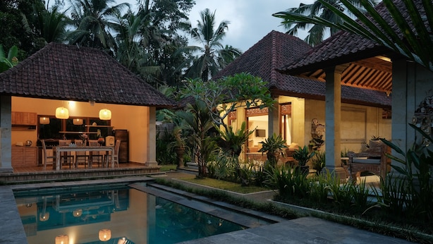 A resort with a swimming pool, outdoor seating, and tropical vegetation.