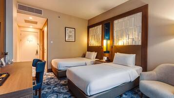 A hotel room with two beds, a desk, and a chair.