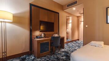 Une chambre d’hôtel avec un lit, un bureau doté d’une télévision, une lampe et une moquette à motifs.