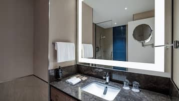 Uma casa de banho moderna com um espelho grande, lavatório e zona de duche.