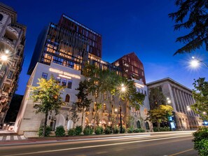 Un hôtel à la façade classique, aux étages supérieurs modernes et à l’entrée bien éclairée.