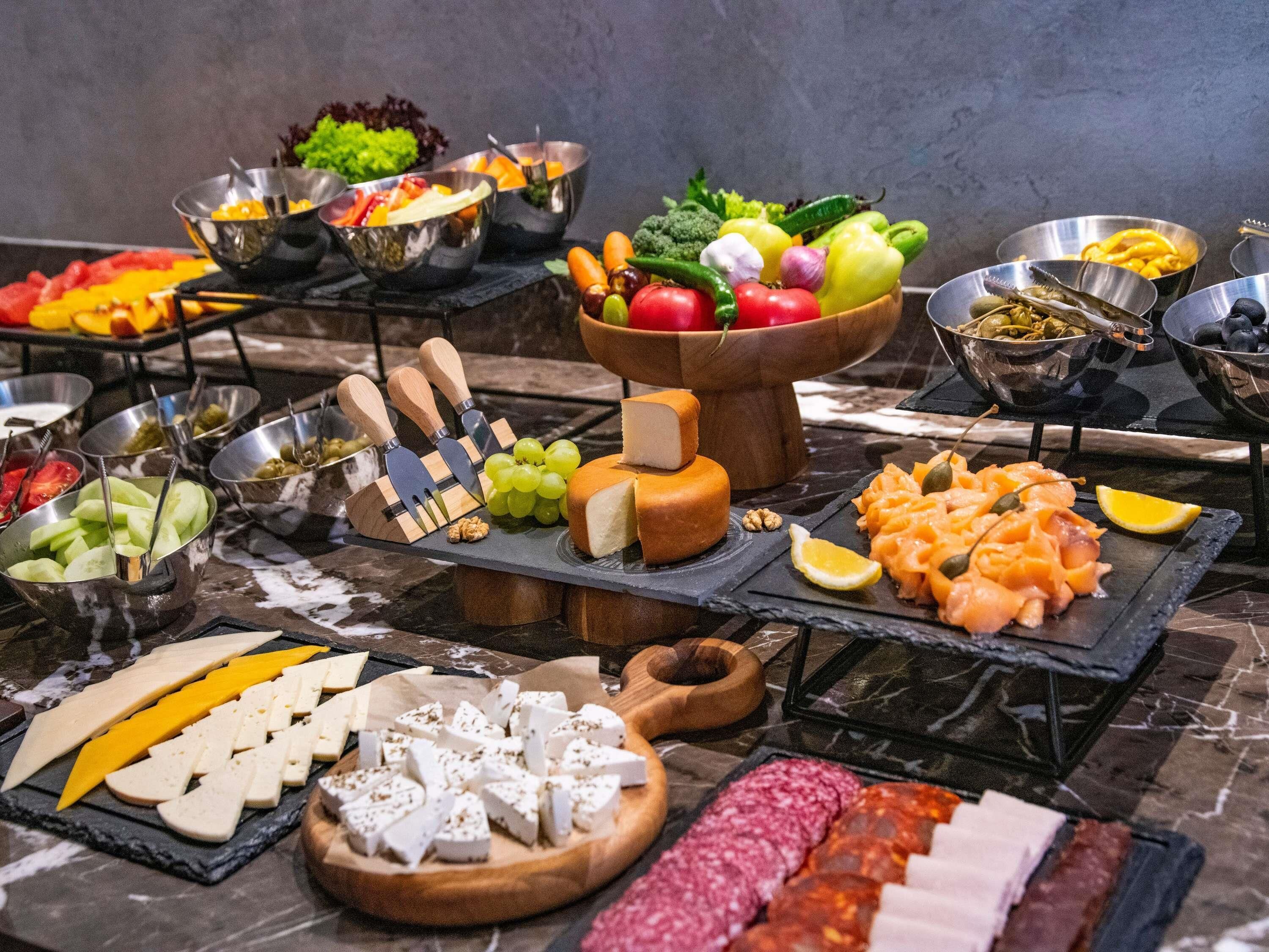 Ein reichhaltiges Buffet mit Käse, Fleisch, Obst und Gemüse.
