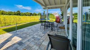 A covered patio with outdoor furniture, a view of a vineyard, and a small outdoor kitchen area. - Die Ausstattung vom Ferienhaus Bauernrose (Vaschwitz)