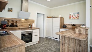 A modern kitchen with wooden countertops, a built-in oven, and a stainless steel range hood. - Die Ausstattung vom Ferienhaus Bauernrose (Vaschwitz)