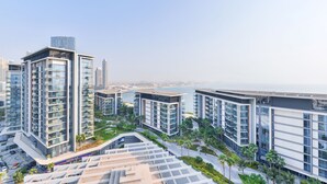Un edificio residenziale a più piani con numerosi balconi, un giardino sul tetto e vista sul mare.