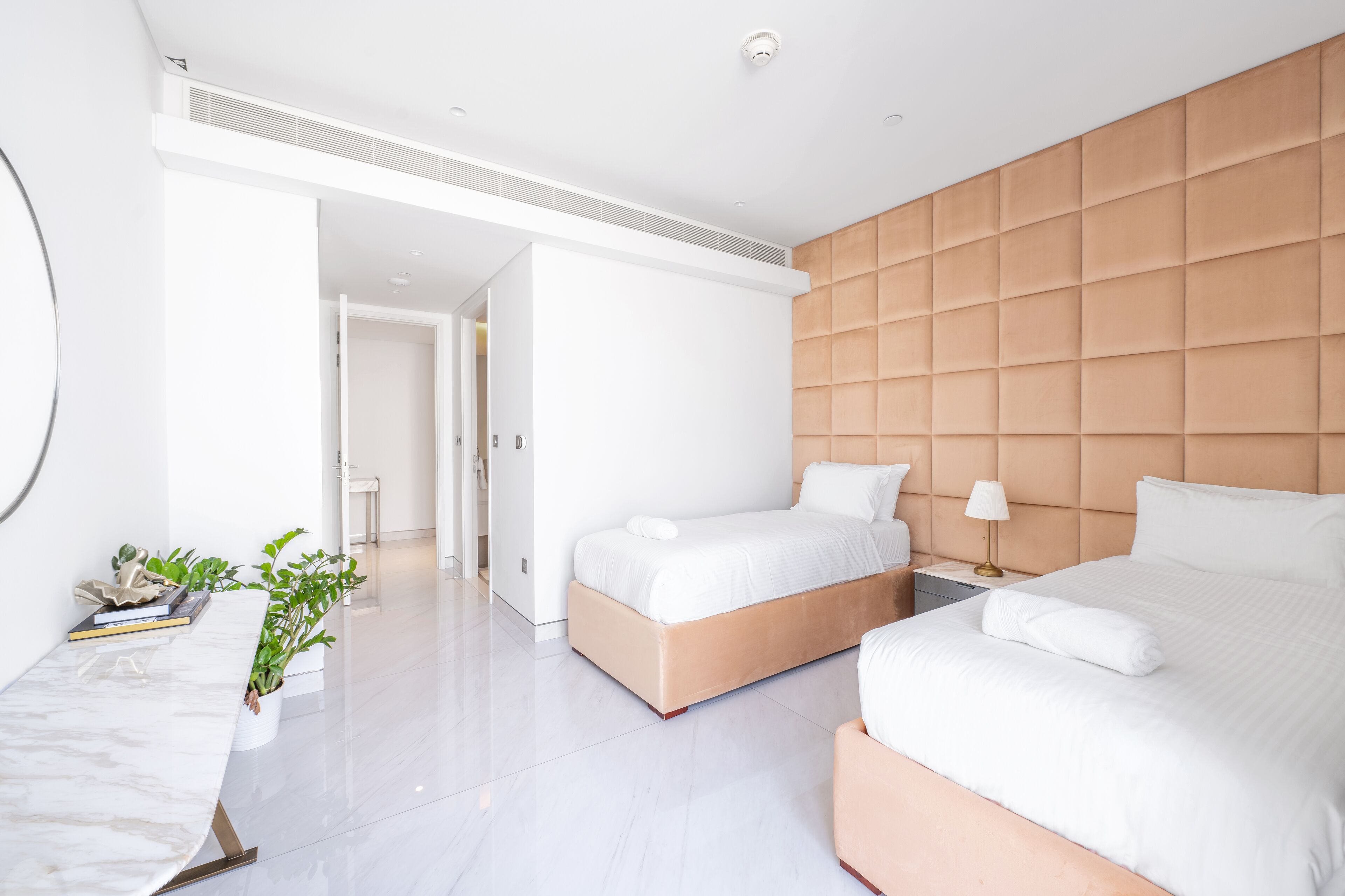 Et moderne hotelværelse med to senge, et marmorbord ved siden af sengen, en potteplante og et stort vindue.