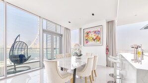 Un'area pranzo moderna con tavolo in vetro, sedie bianche e vista sulla città.