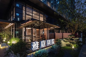 A modern building with a glass facade, outdoor seating area, and a sign with Chinese characters. - Shenzhen Yating Fengnian Hotel (Shenzhen)