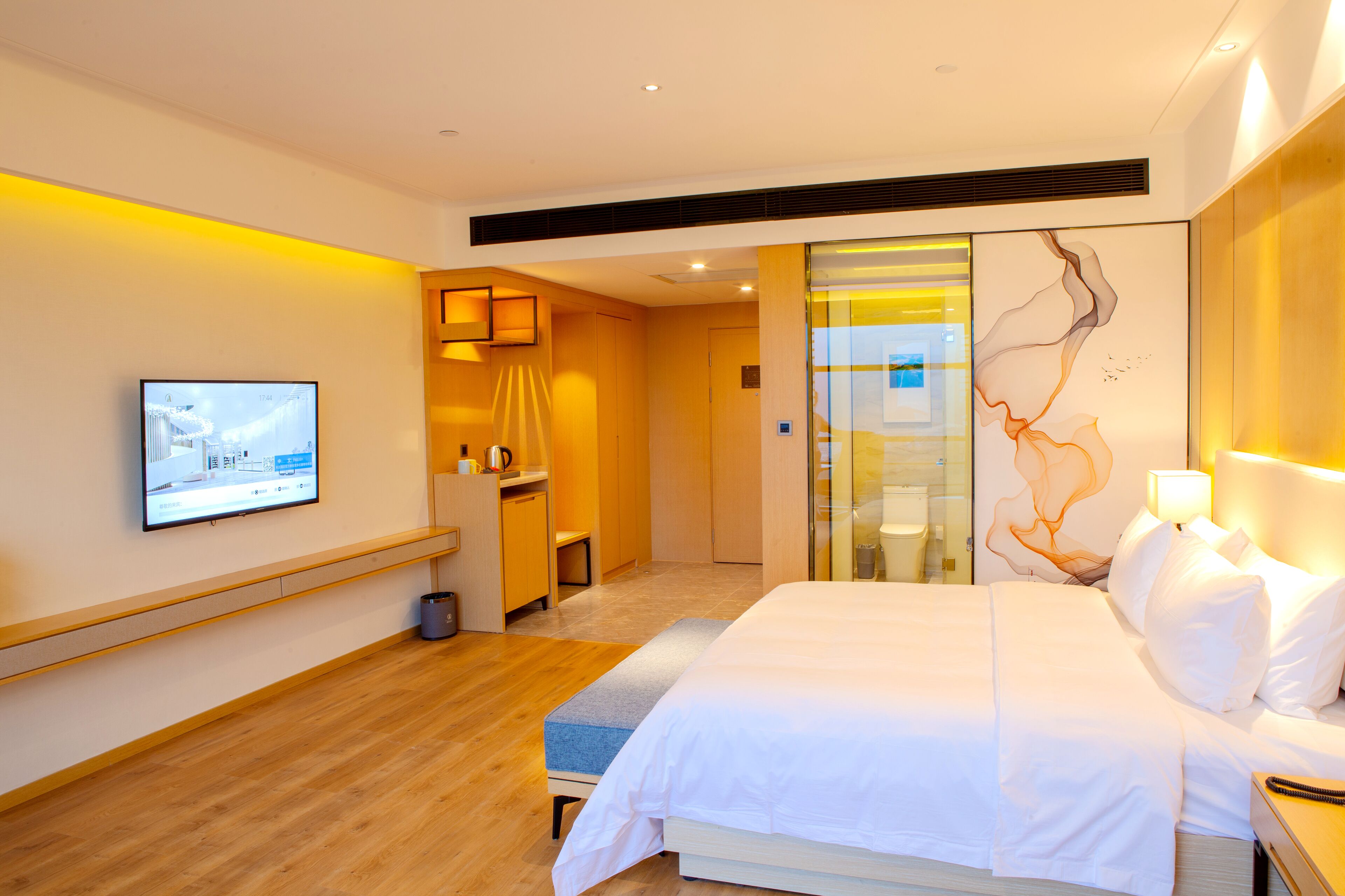 Habitación de hotel moderna con una cama grande, un escritorio y un televisor fijado en la pared.