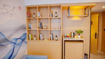 A modern room with a built-in bookshelf, a small kitchenette, and a wall mural.