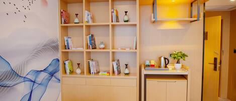 A modern room with a built-in bookshelf, a small kitchenette, and a wall mural.