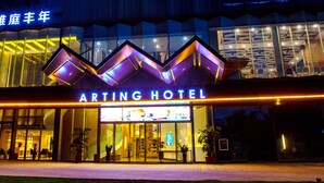 Exterior del Arting Hotel con diseño moderno, destacando una entrada principal y señalización iluminada.