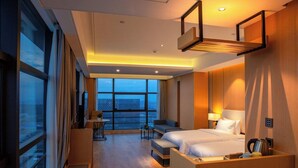 Una habitación de hotel con un ventanal grande, una cama, un sofá, un escritorio y una silla.