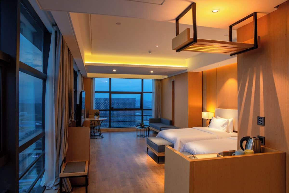 Ett hotellrum med ett stort fönster, en säng, en soffa, ett skrivbord och en stol.