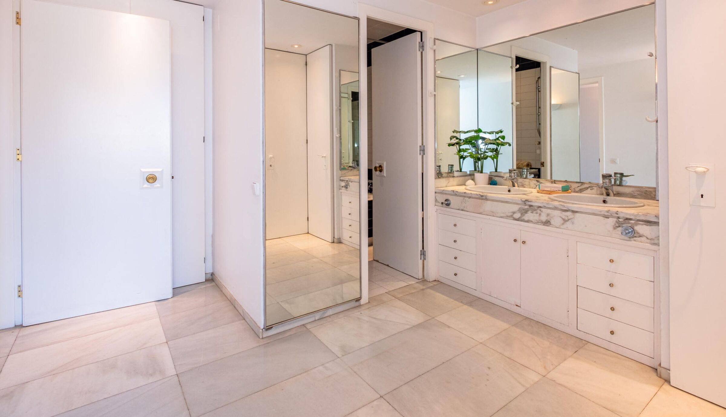 Une salle de bain moderne dotée d’un meuble-lavabo double, de grands miroirs et d’une douche à l’italienne.