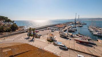 Un puerto deportivo costero con barcos amarrados, cielo despejado y una carretera que lleva al puerto.
