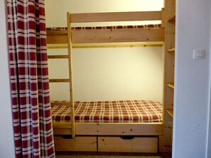 Un lit superposé avec un matelas à carreaux et une structure en bois.