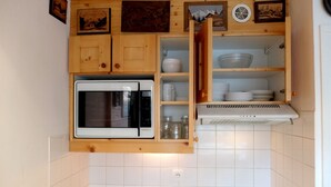 Une cuisine compacte équipée d’un four à micro-ondes encastré, d’un évier et d’une cuisinière.
