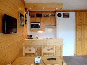 Interior de madera con área de cocina, que incluye un microondas, estufa y armarios de madera.
