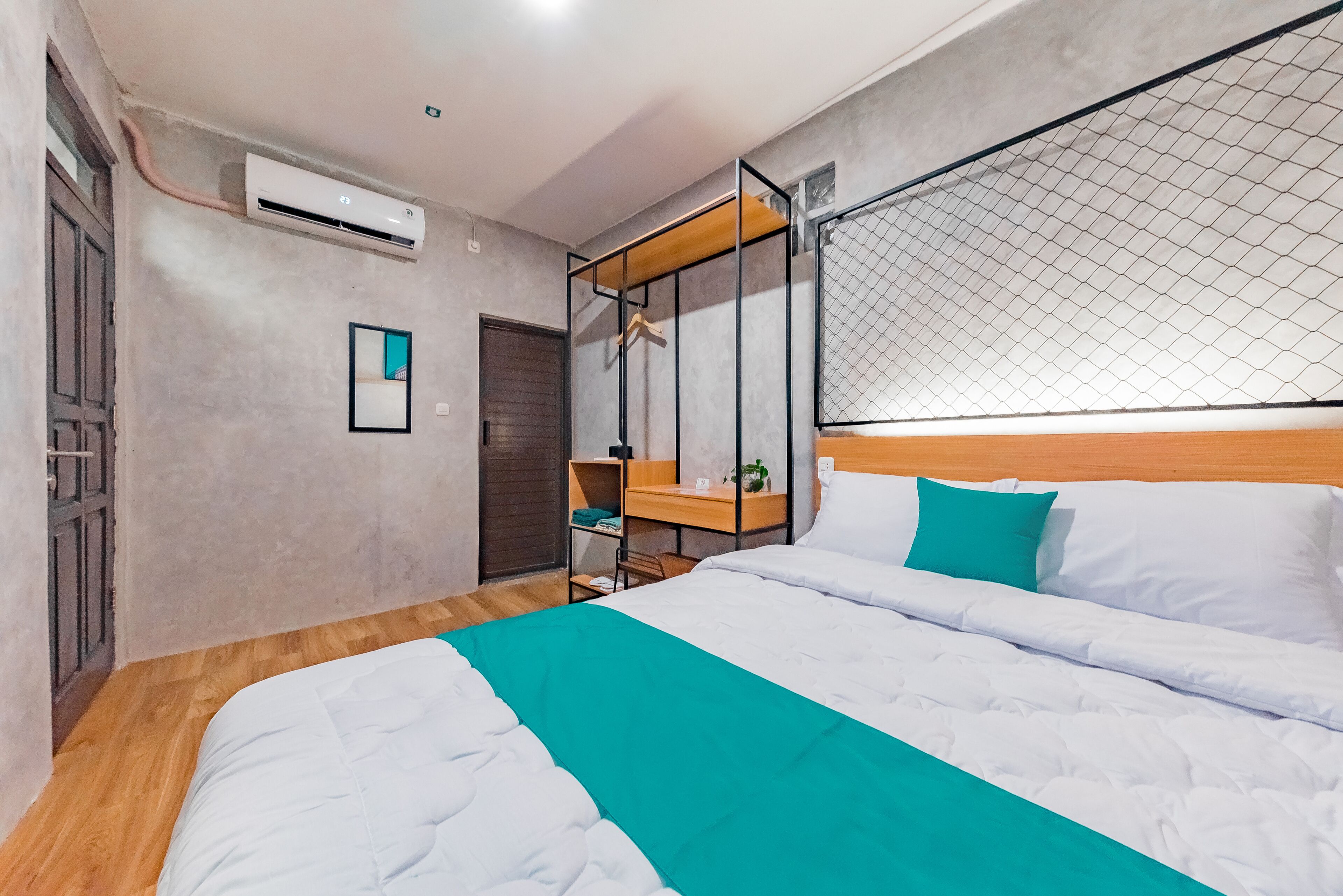 Een moderne hotelkamer met een groot bed, een houten hoofdbord, een zwevend schap en een klein bureau.