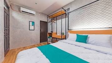 Een moderne hotelkamer met een groot bed, een houten hoofdbord, een zwevend schap en een klein bureau.