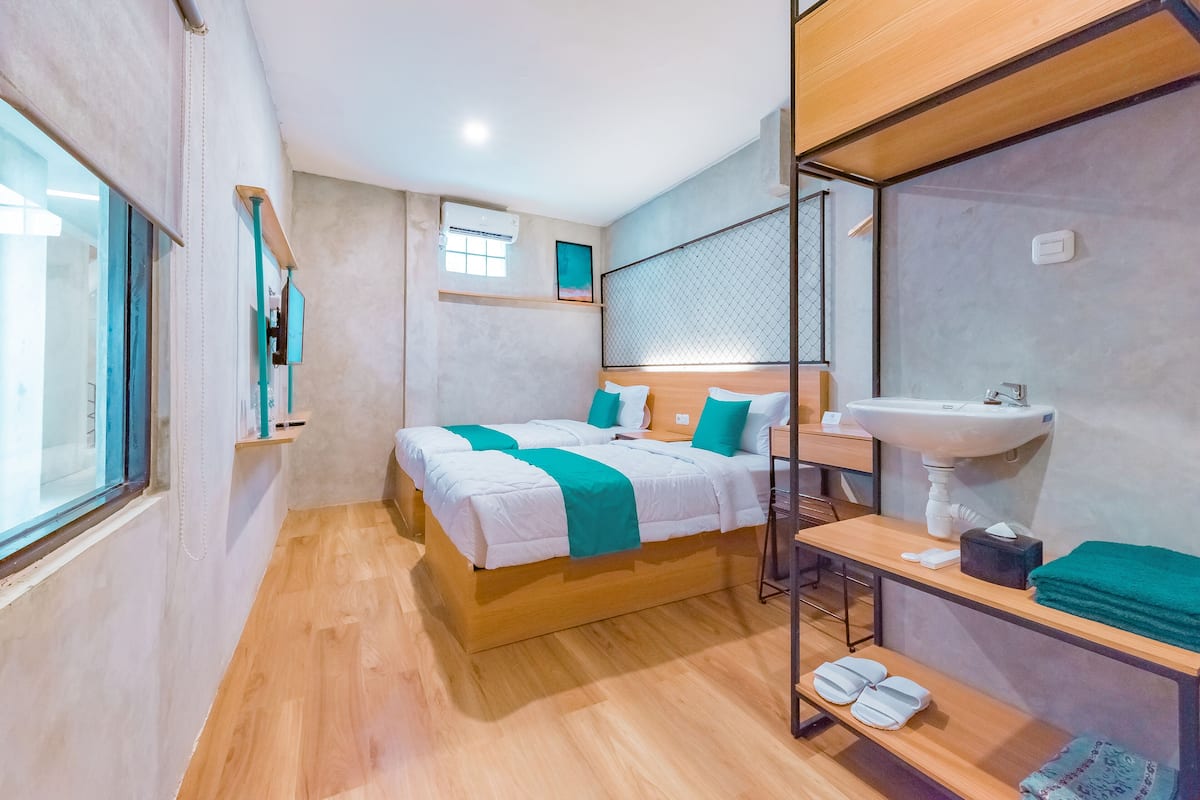 A modern hotel room with a wooden bed, a built-in sink, and a window with blinds.