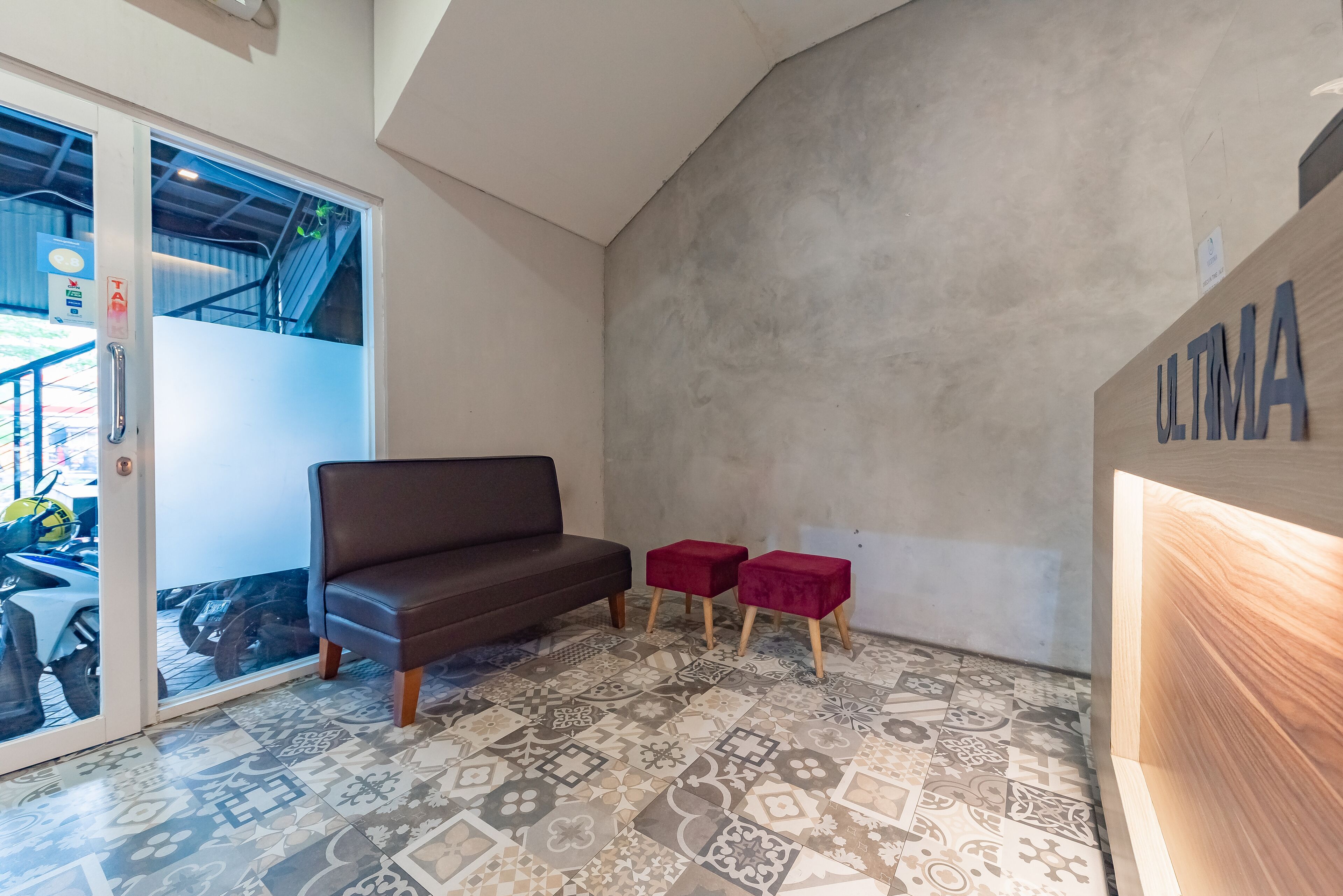 A modern interior with a brown sofa, two red stools, and a patterned floor.