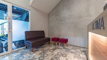 A modern interior with a brown sofa, two red stools, and a patterned floor.