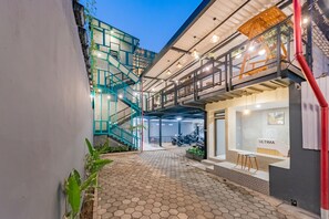 A modern building with a staircase, a reception desk, and a bike parking area. - Ultima Guest House (Bandung)