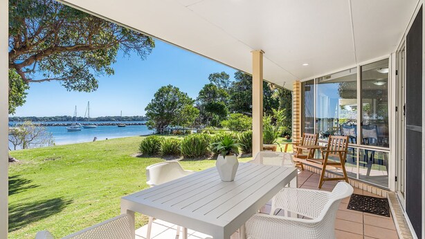 A covered patio with a table and chairs, overlooking a marina with boats and a clear view of the water. - River Luxury - Set right on Iluka Bay (Iluka)