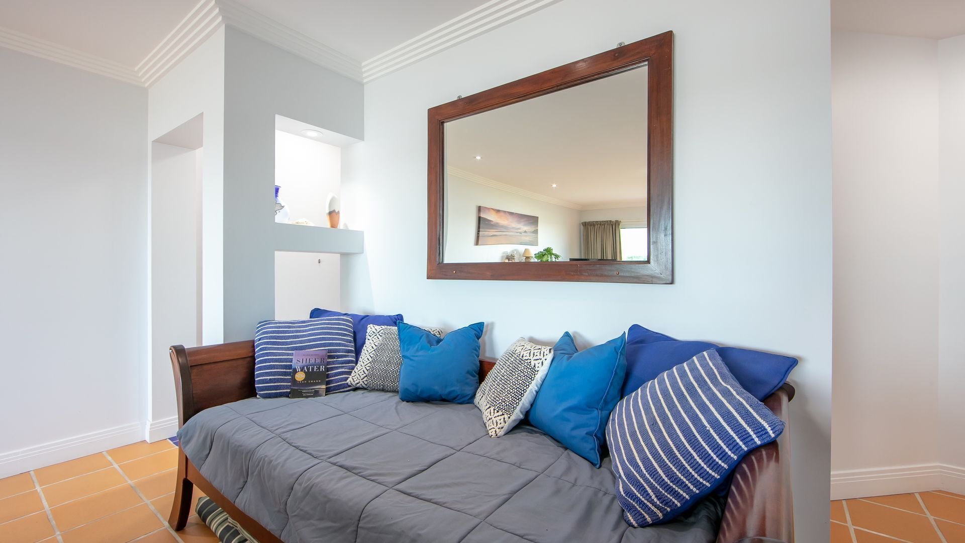 A bedroom with a bed, pillows, a large mirror, and a view of the bathroom.