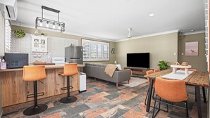 Een moderne keuken met een bar, een grijze bank en een eettafel met stoelen.