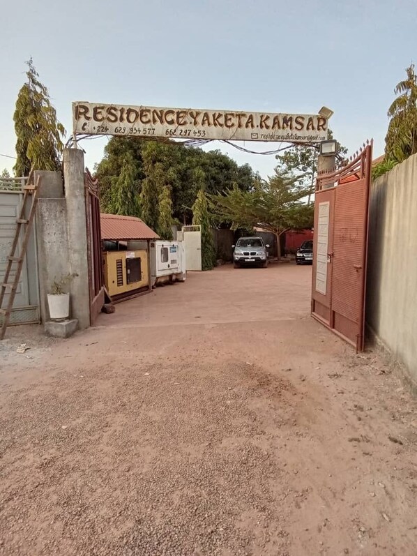 Una entrada protegida por un portón con un letrero que dice 'RESIDENCEYA KAMSA'.