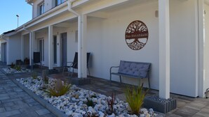 A building with a white exterior, a circular logo on the wall, and a bench outside. - Spacious holiday home with sauna, mountain view and garden in Lechbruck am See (Lechbruck)