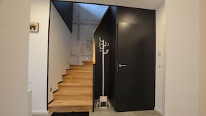 A staircase leading to a dark room with a coat rack and a door. - Spacious holiday home with sauna, mountain view and garden in Lechbruck am See (Lechbruck)