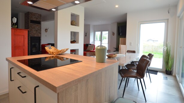A modern kitchen with an island, built-in oven, and a dining area with chairs and a table. - Spacious holiday home with sauna, mountain view and garden in Lechbruck am See (Lechbruck)