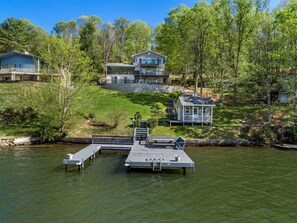 A lakeside property with a dock, a small cabin, and a main house surrounded by trees. - Owens Oasis, lake front, fire pit, two decks. (Radford)
