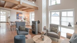 Ein großzügiges Wohnzimmer mit hohen Decken, einem Kamin und großen Fenstern.