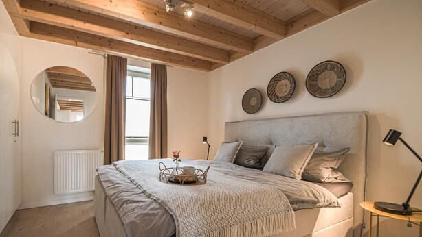 Ein Schlafzimmer mit einem Bett, einem runden Spiegel, einem Heizkörper und drei Wandbildern.