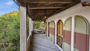 A wooden covered porch with a hammock, arched windows, and a wooden floor. - Incredible Coastal Castle on Sullivans Island (Sullivans Island)